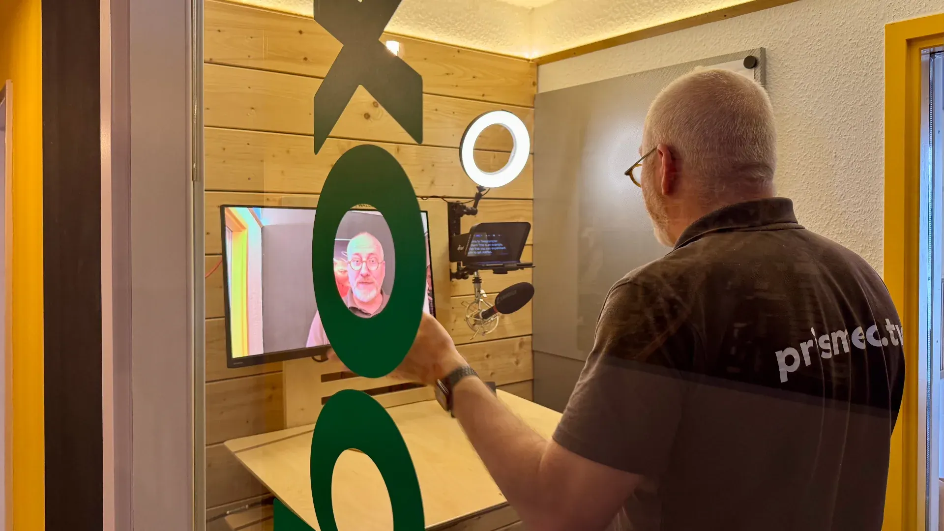 Box – Aufnahme-Setup in der Box mit Blick durch die Glastür auf einen Sprecher vor Kamera