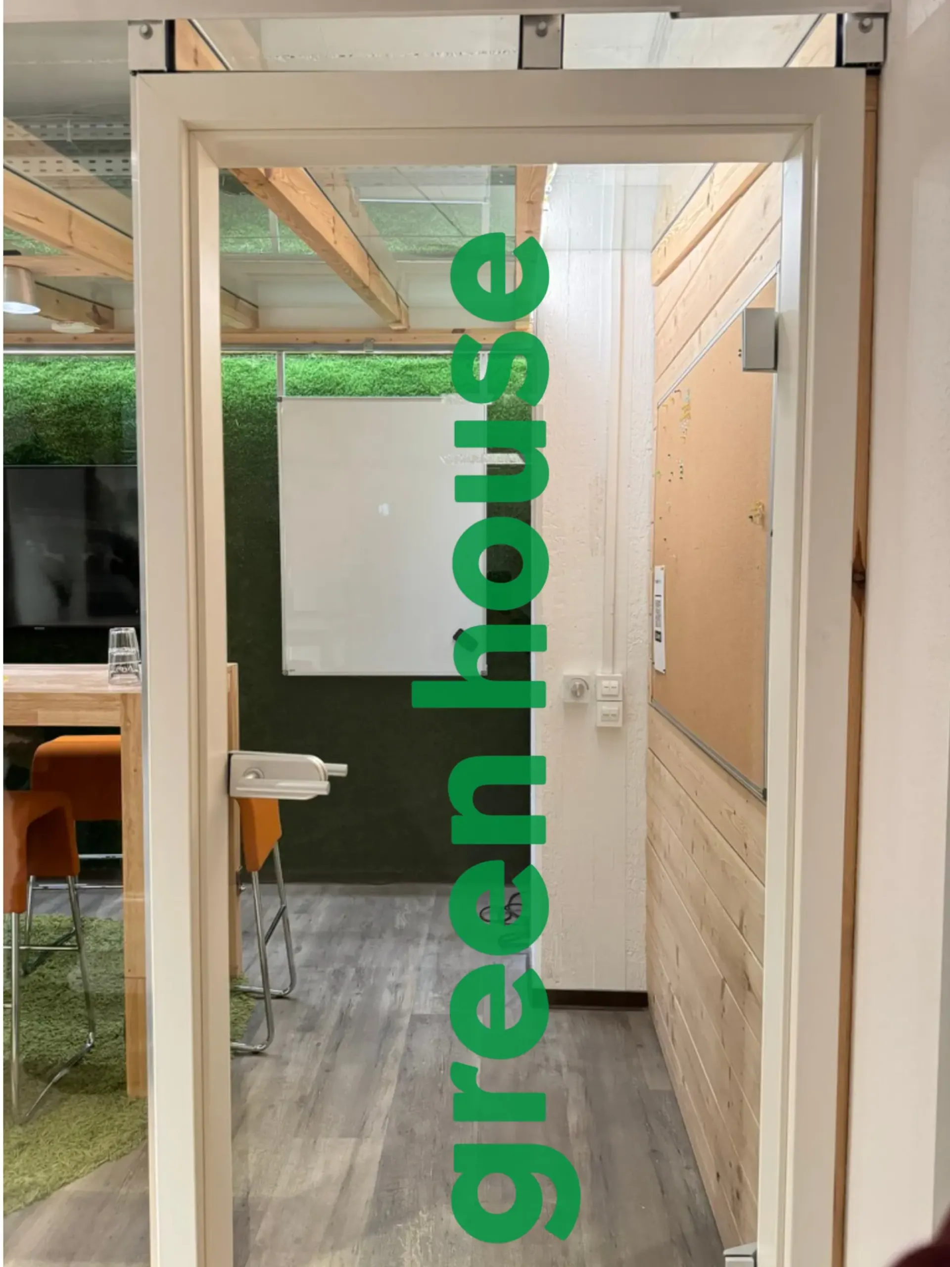 Greenhouse – Eingang zum Greenhouse mit grünem greenhouse-Schriftzug auf Glastür
