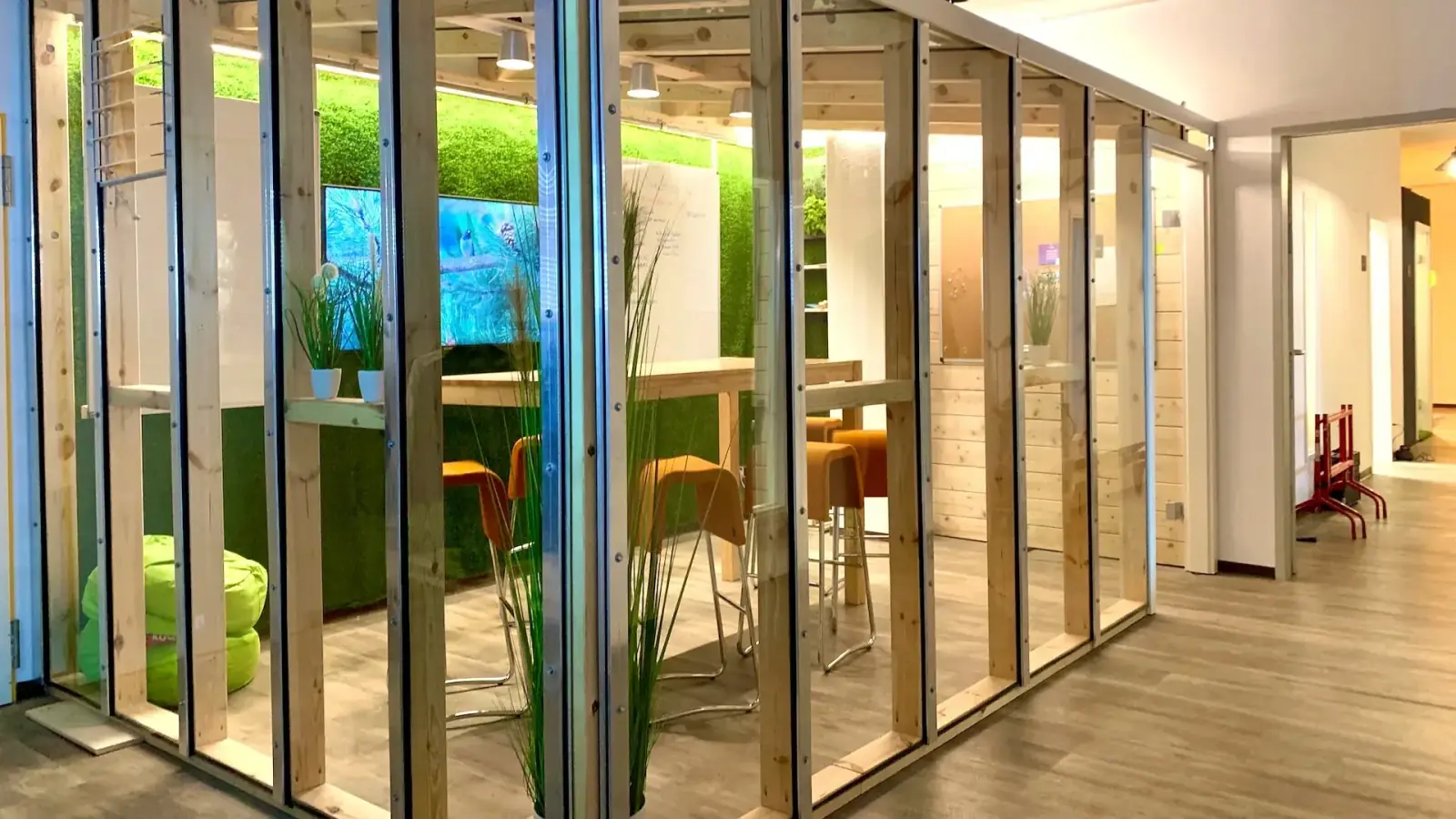 Greenhouse – Greenhouse im Prismeo LAB Hamburg HafenCity – Außenansicht mit Holzrahmen, Glaswänden und grüner Pflanzenwand