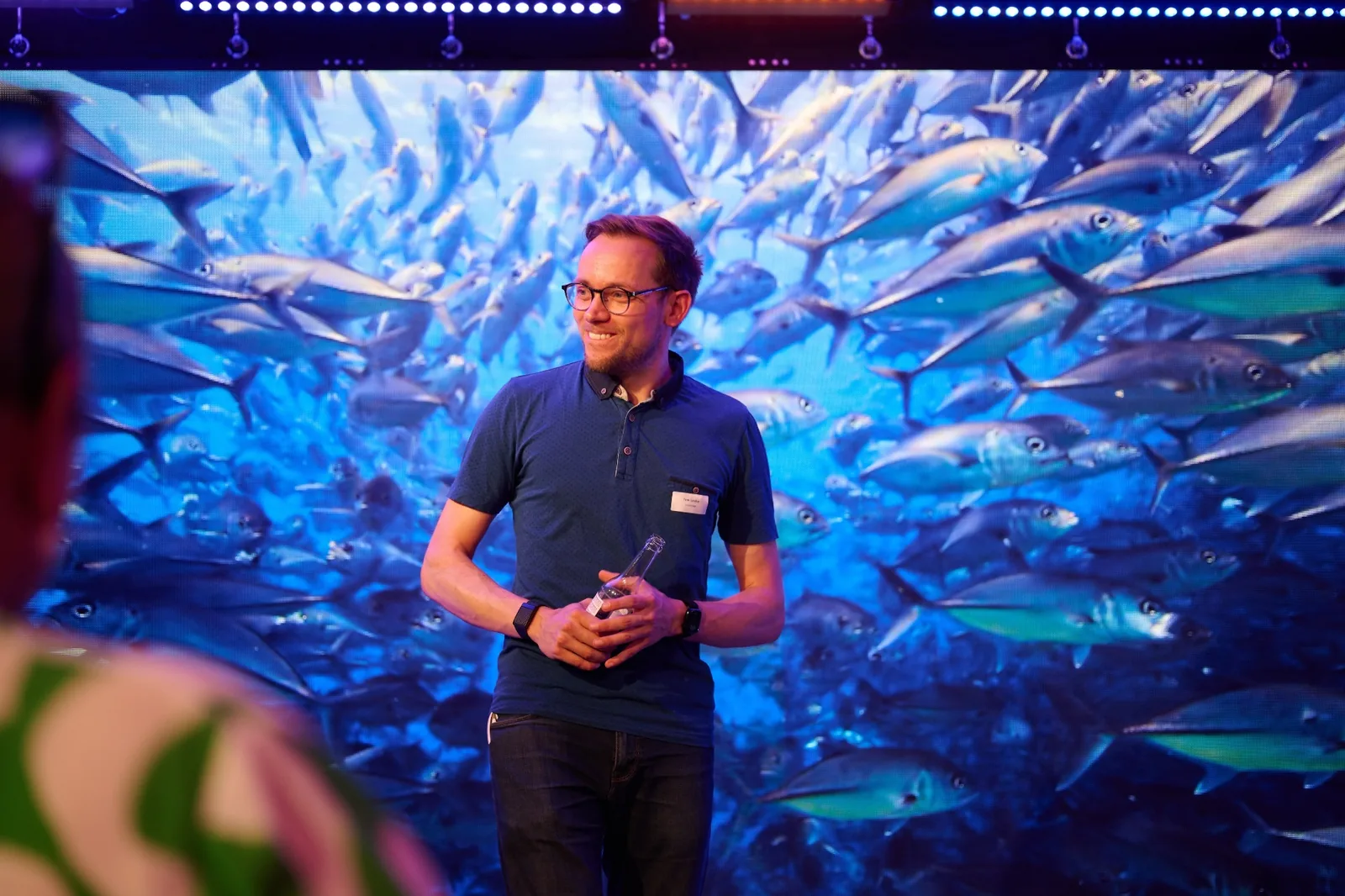 Tom Lerche, Sprecher der Interessengemeinschaft HafenCity e.V., im Showroom des Prismeo LAB vor der großen LED-Wand mit Fischschwarm-Motiv.