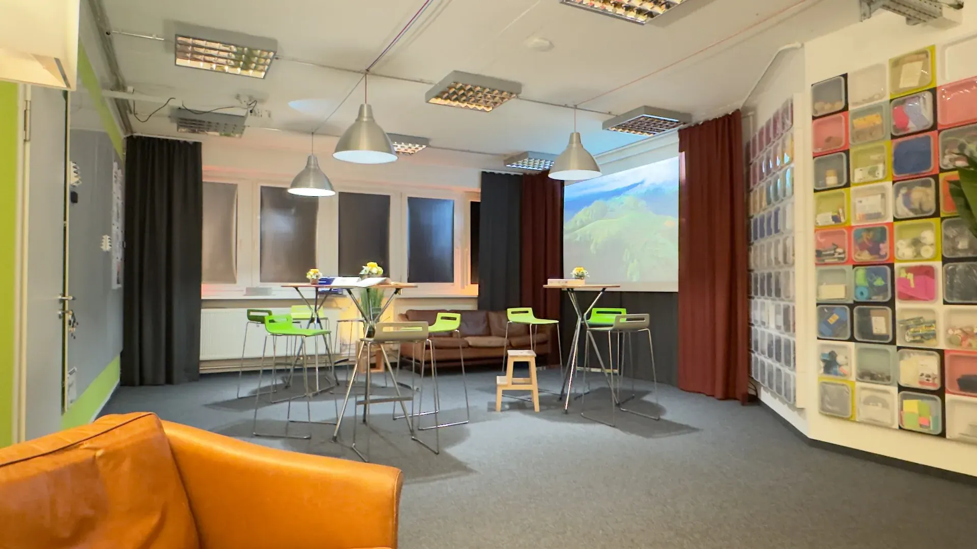 Idealab – Idealab mit Beamer-Projektion, Ledercouch und Stehtischen für hybride Workshop-Formate