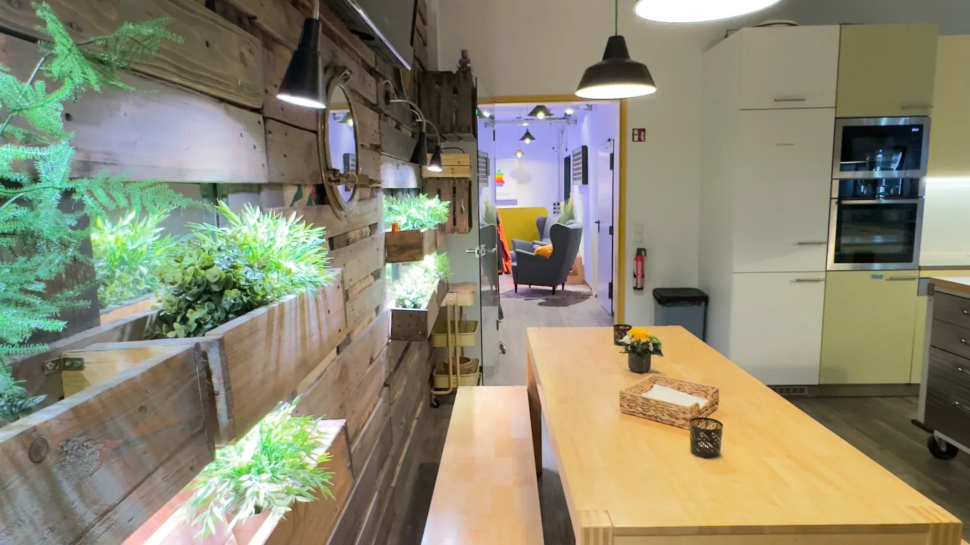 Kitchen – Blick entlang der Kitchen-Theke mit grüner Pflanzenwand und Durchgang zum Loft