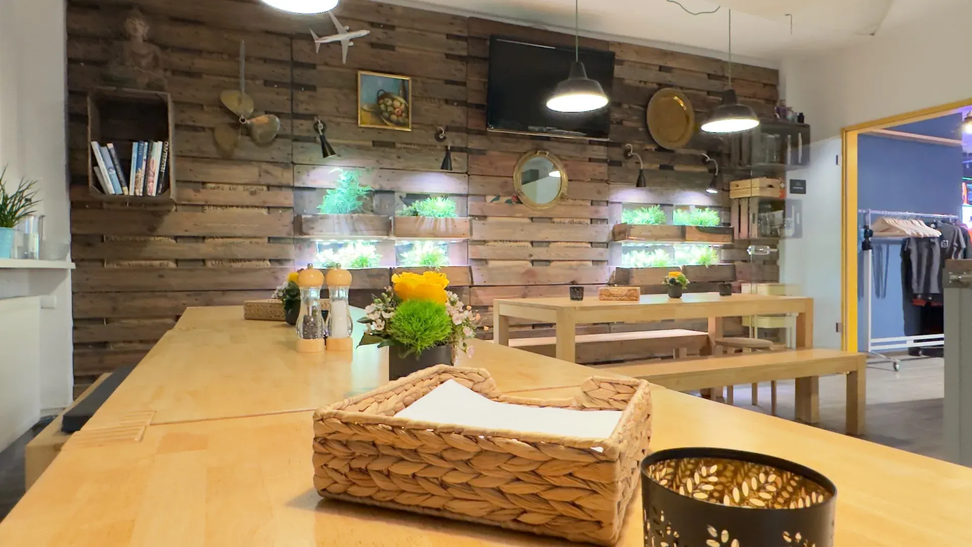 Kitchen – Langer Holztisch in der Kitchen vor Palettenwand, vorbereitet für eine gemeinsame Tafel