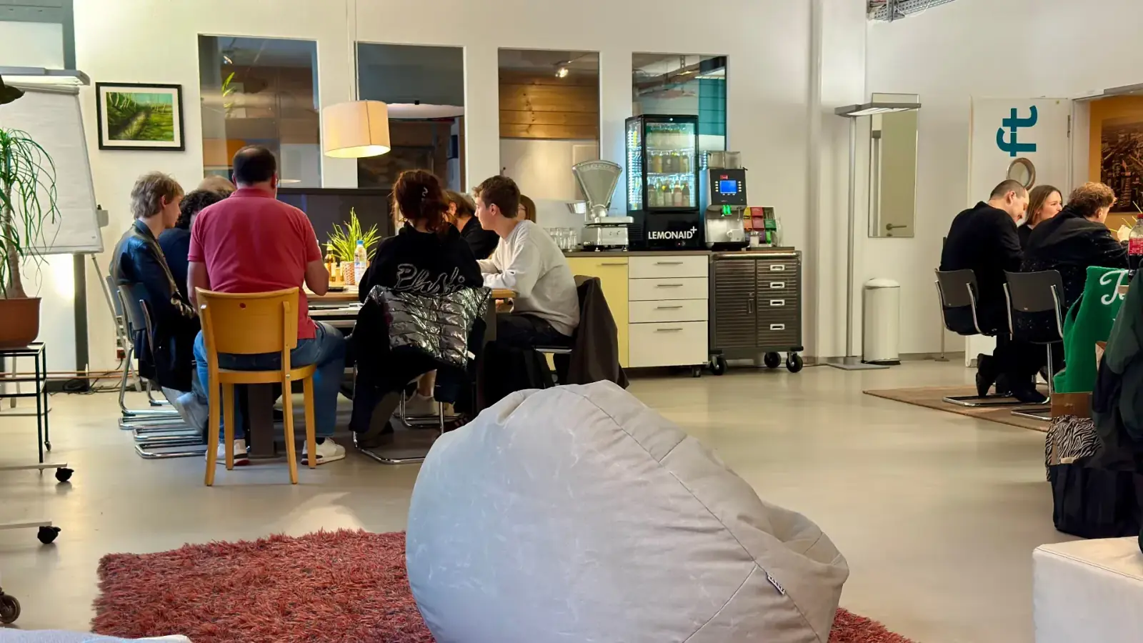 Loft – Catering-Situation im Loft: Gruppe an Tischen mit Kaffeevollautomat, Flaschenkühlschrank und Snacks