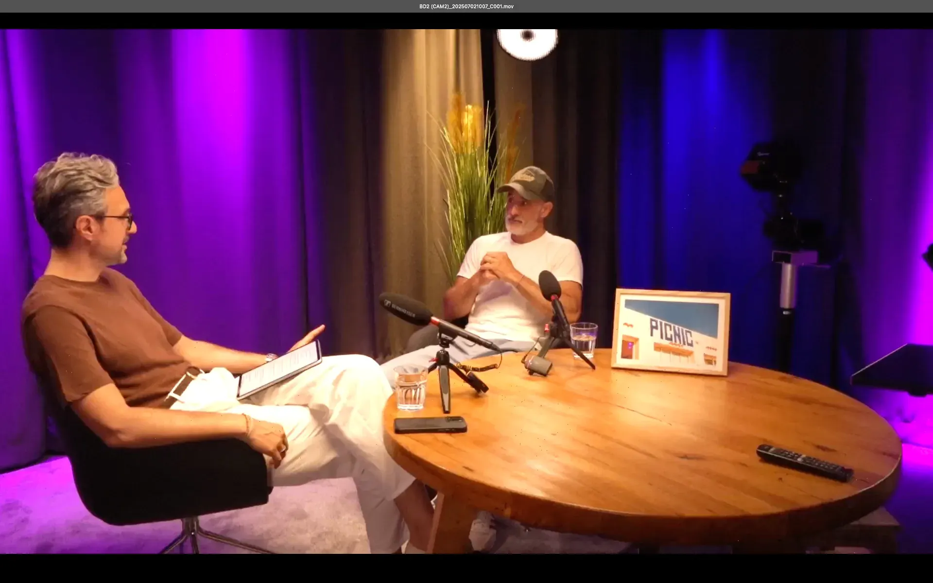 Studio – Interview-Aufnahme im Studio mit zwei Gesprächspartnern am runden Holztisch, Sennheiser-Mikrofonen und Tablet
