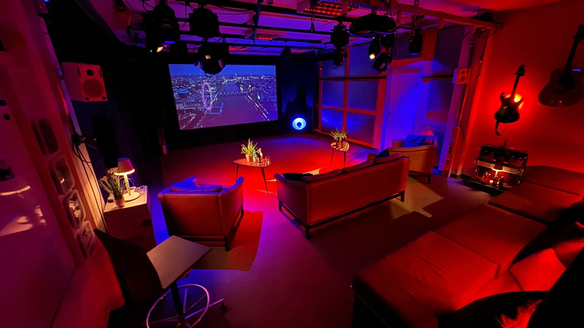 Theater – Theater im Prismeo LAB in stimmungsvoller rot-blauer Beleuchtung mit Leinwand, Lounge und Instrumenten