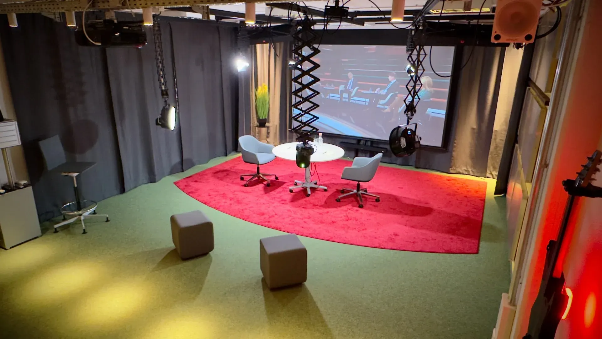 Theater – Hybrides Talk-Setup im Theater mit zwei Sesseln, rundem Tisch und großer Leinwand für Live-Übertragungen