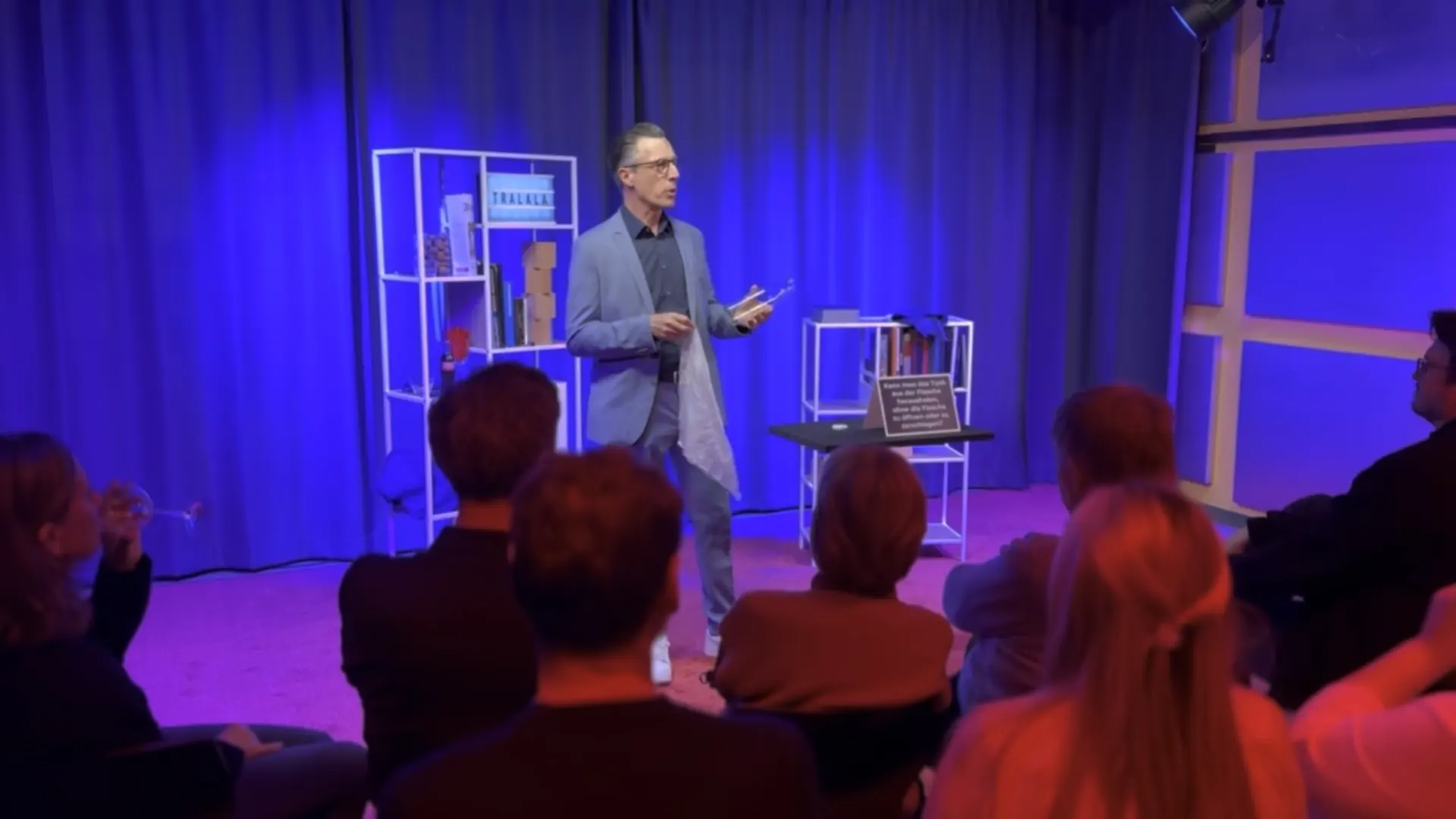 Theater – Zaubershow im Theater des Prismeo LAB mit Künstler auf der Bühne, blau beleuchtetem Vorhang und konzentriertem Publikum im Halbkreis