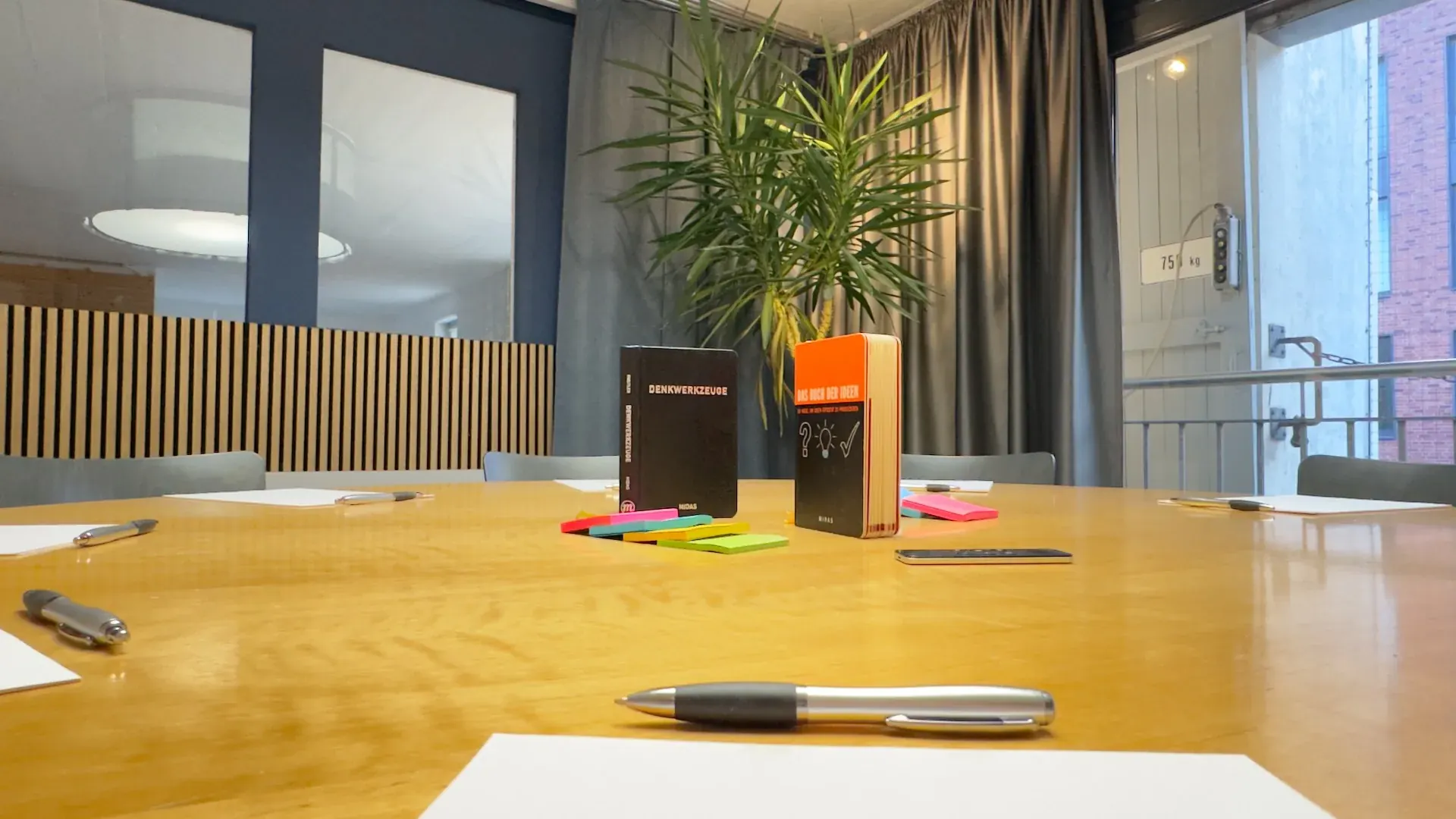 Thinktank – Tischdetail im Thinktank mit den Büchern 'Denkwerkzeuge' und 'Das Buch der Ideen', Post-its und Stiften