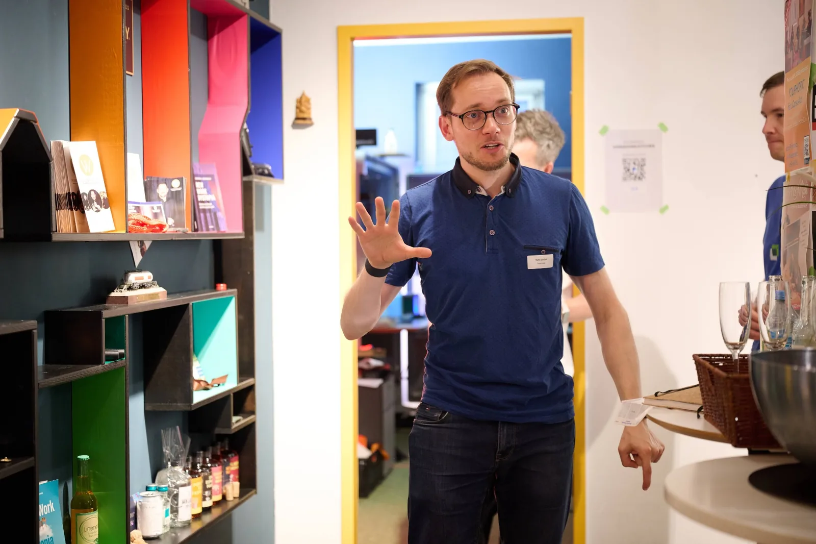 Tom Lerche im Gespräch während der Führung durch das Prismeo LAB, vor einem farbigen Setzkasten mit kleinen Fundstücken.