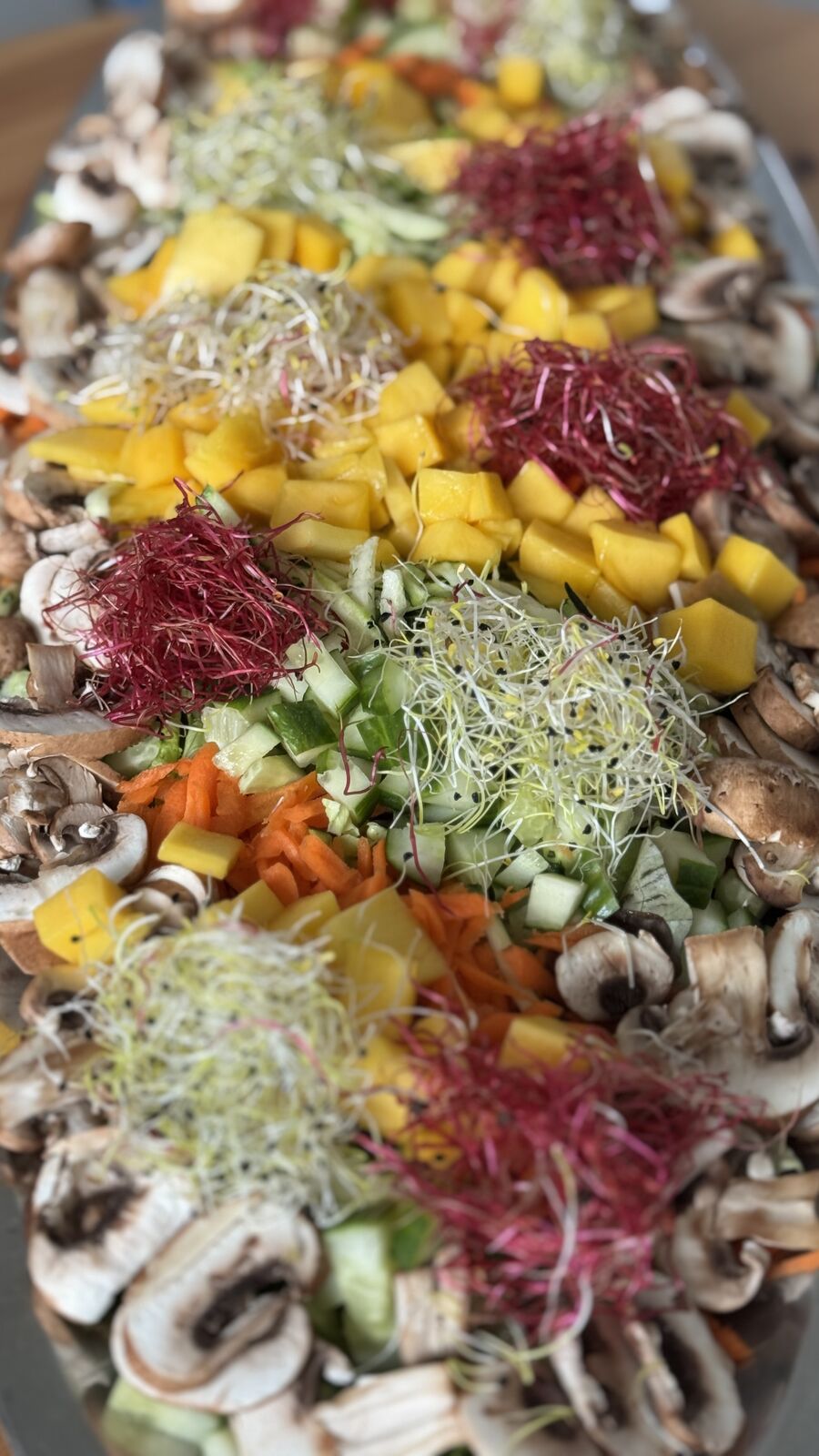 Rohkost-Buffet mit Pilzen, Karotten, Gurken, Mango und Sprossen