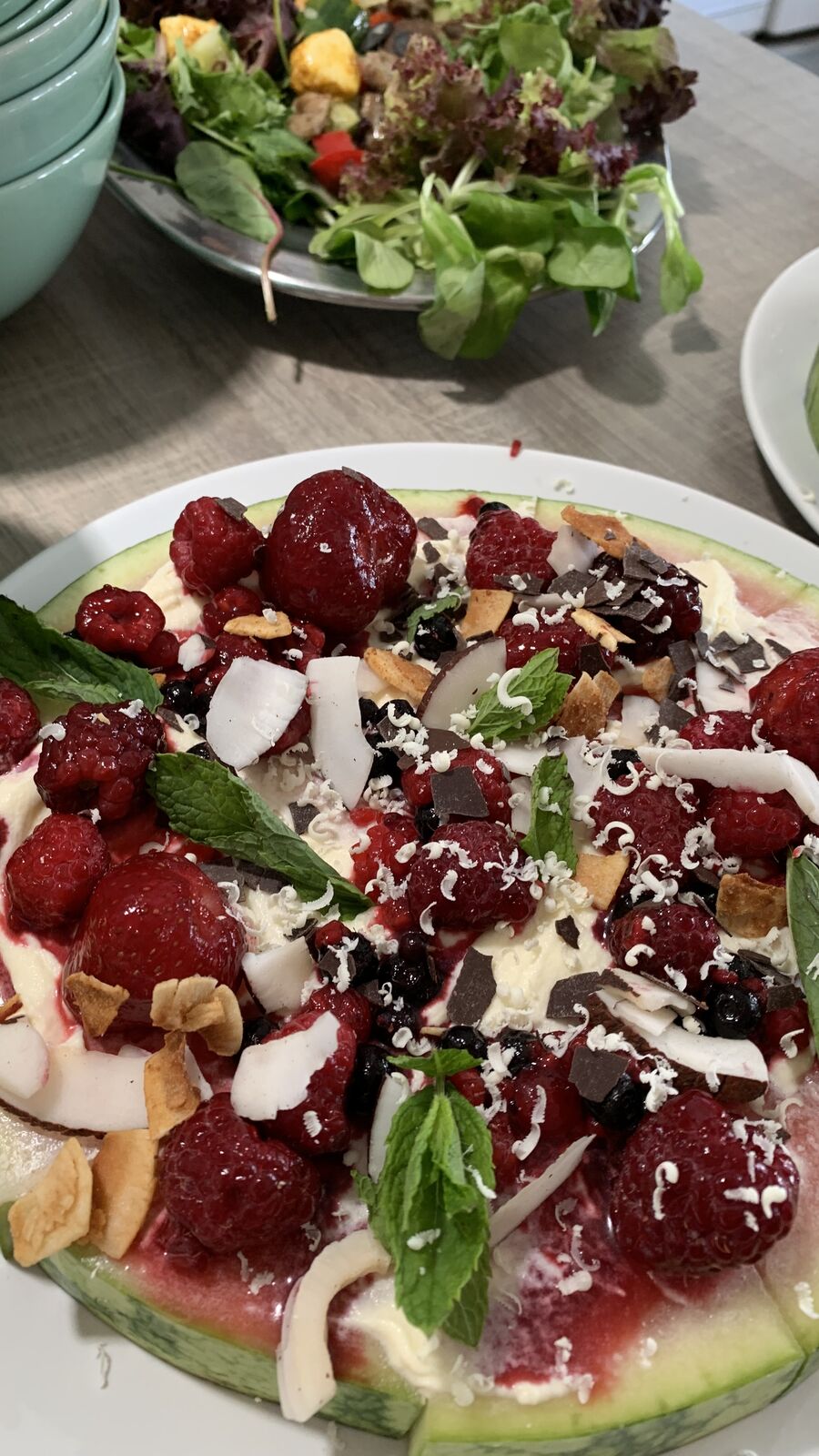 Wassermelonenpizza belegt mit Beeren, Kokosnussflocken und Minze