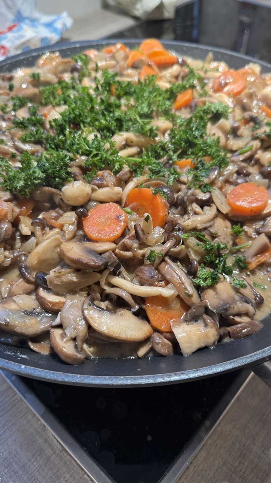 Pilzpfanne mit Karotten und Kräutern, in einer Pfanne angerichtet, asiatisch inspiriert.