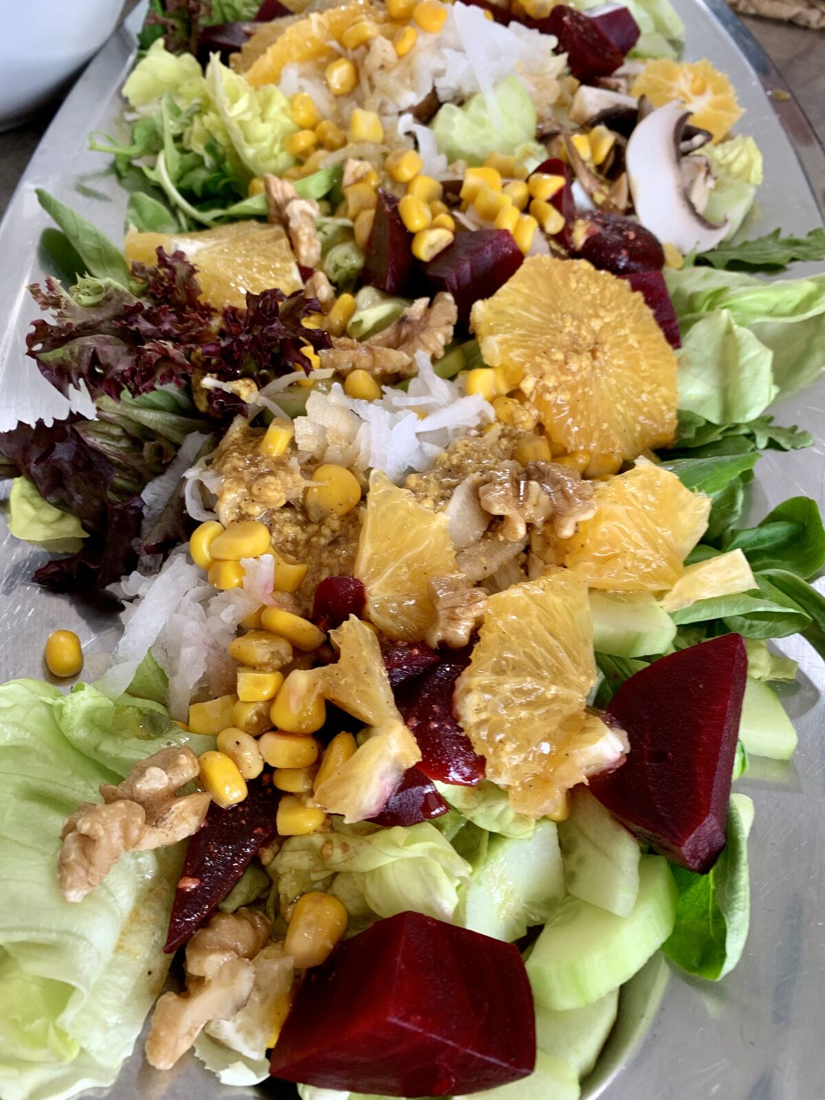 Bunter Salat mit Orangen, Roter Bete, Mais, Walnüssen und Blattsalaten auf Servierplatte