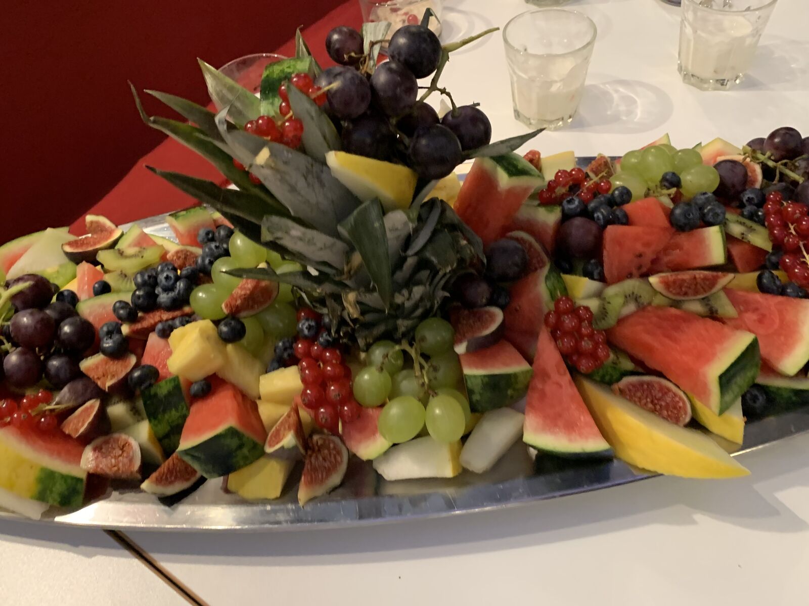 Eine große Platte mit verschiedenen frischen Früchten wie Wassermelone, Weintrauben, Feigen und Beeren.