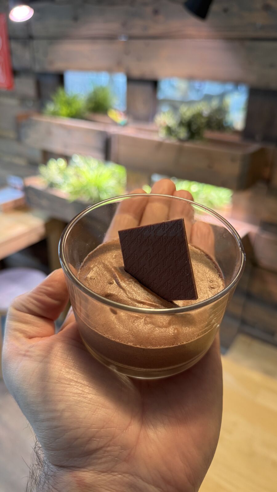Schokoladenmousse in Glas mit Lindt Schokolade, von Hand gehalten.
