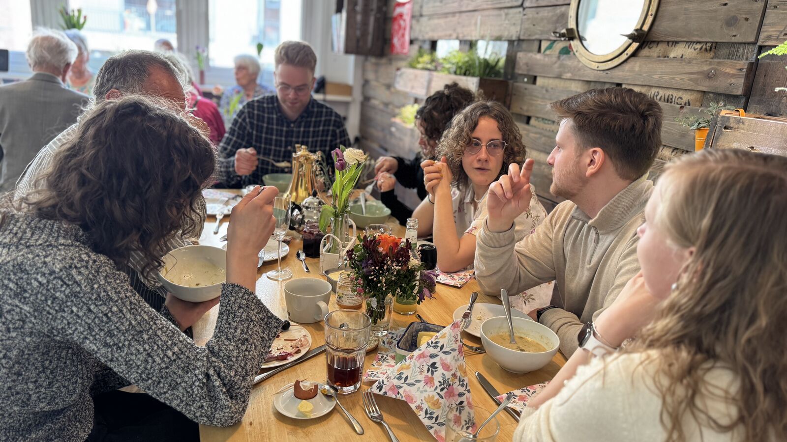 Personen am Tisch beim Mittagessen in entspannter Atmosphäre.