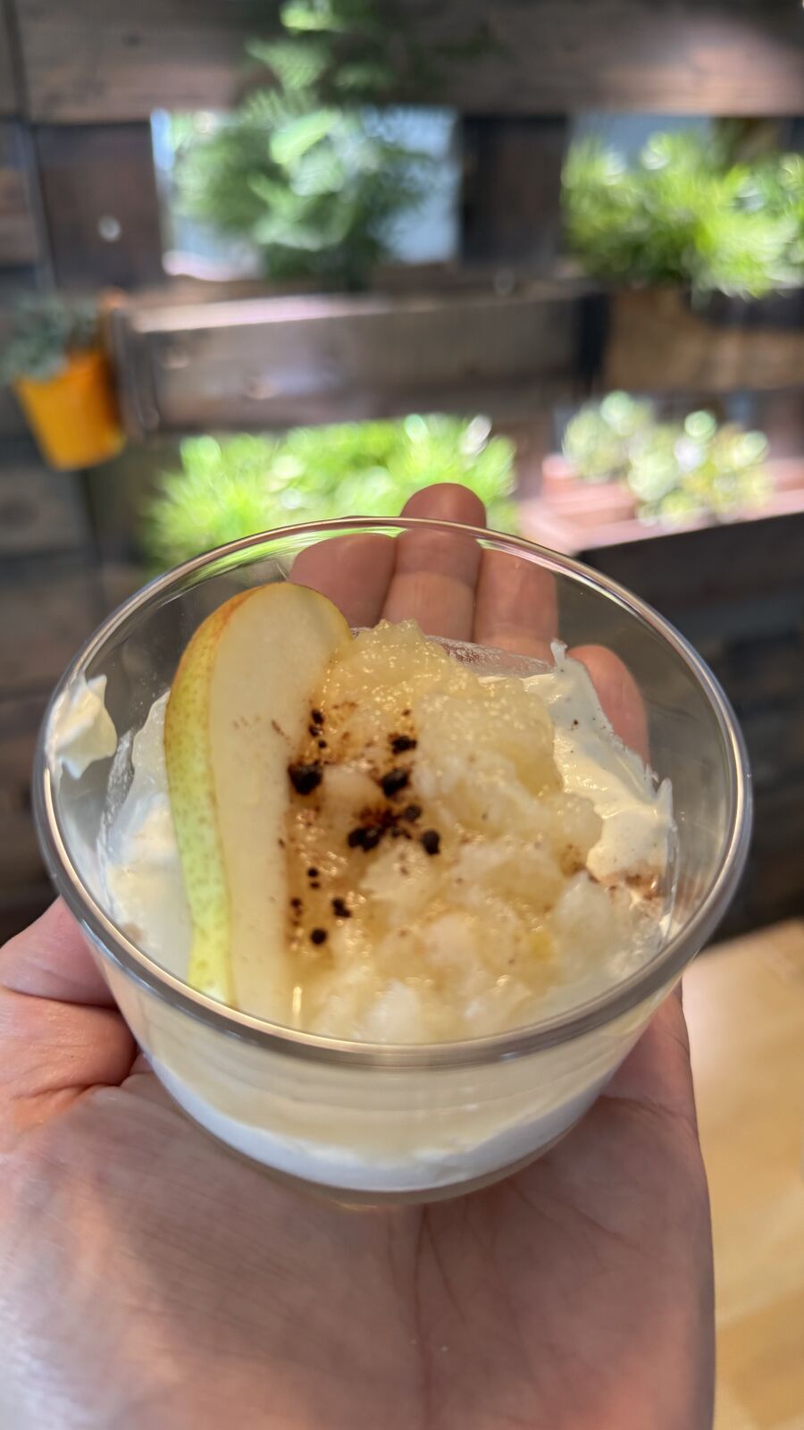 Dessert im Glas mit Birne und karamellisiertem Zucker, gehalten in einer Hand