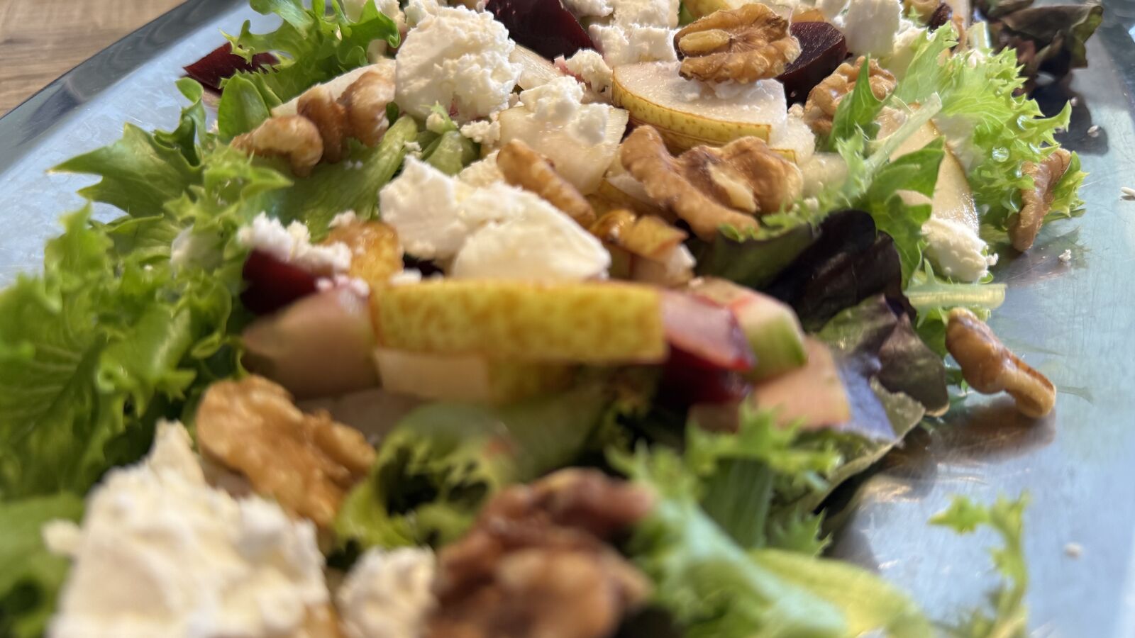Salat mit Feta, Walnüssen und Birnenstücken auf einem länglichen Tablett