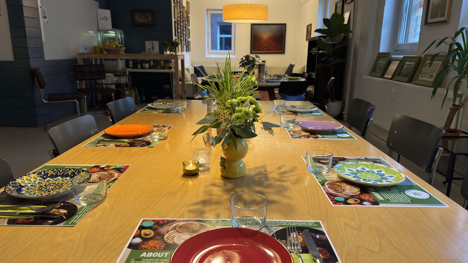 Gedeckter Esstisch im Restaurant mit bunten Tellern und Blumendeko