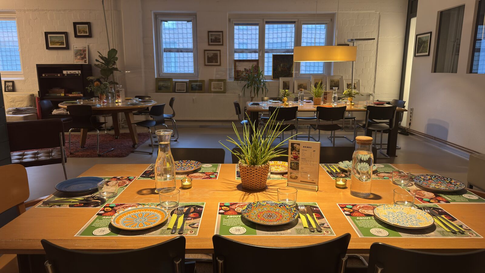Gedeckter Tisch mit bunten Tellern und Gläsern in einem modern eingerichteten Raum.