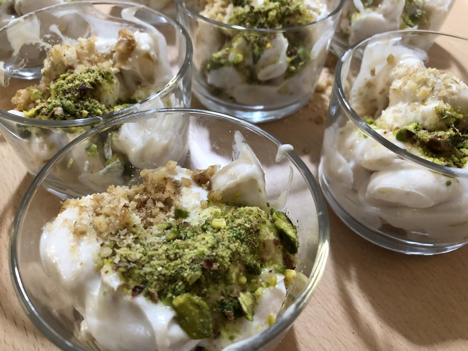 Dessert aus Creme mit Pistazien und Nüssen in kleinen Gläsern.