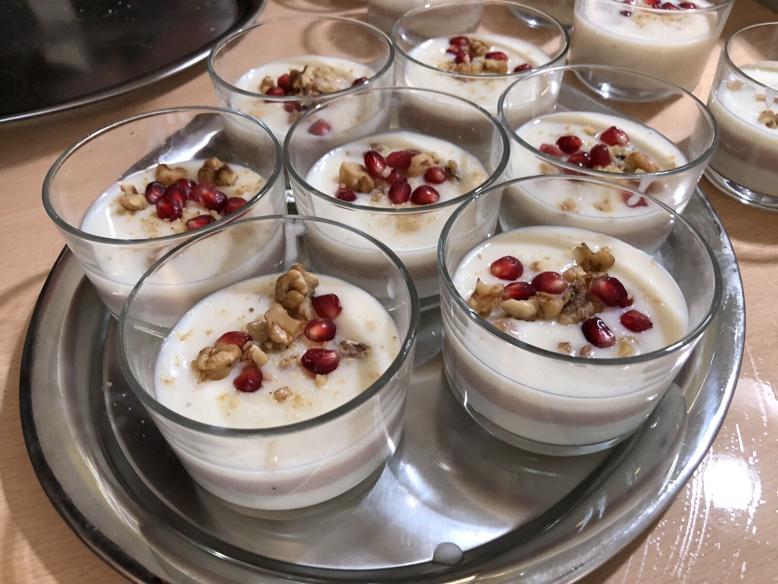 Dessert aus mehreren Gläsern mit Creme, Walnüssen und Granatapfelkernen