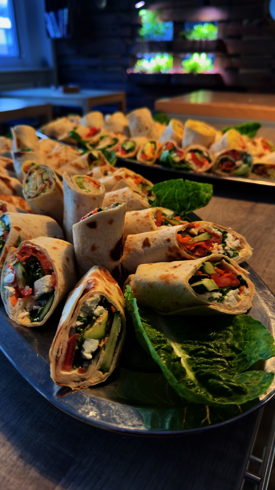 Wraps mit Gemüsefüllung, Feta und Huhn angerichtet auf einem Buffet.