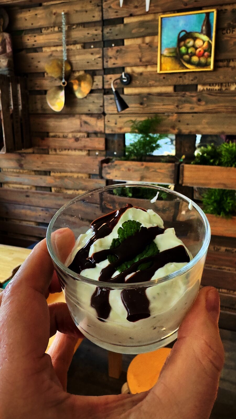 Dessert im Glas mit Schokosauce und Minze in der Hand