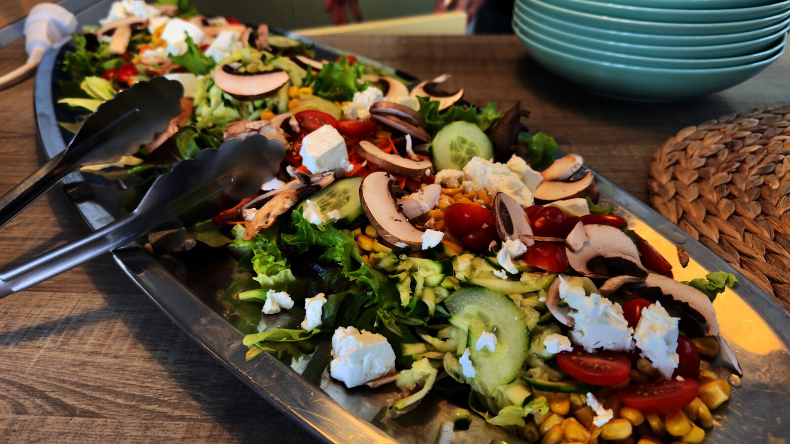 Bunter Salat mit Blattsalat, Pilzen, Feta, Tomaten und Gurke in einer Edelstahlschale