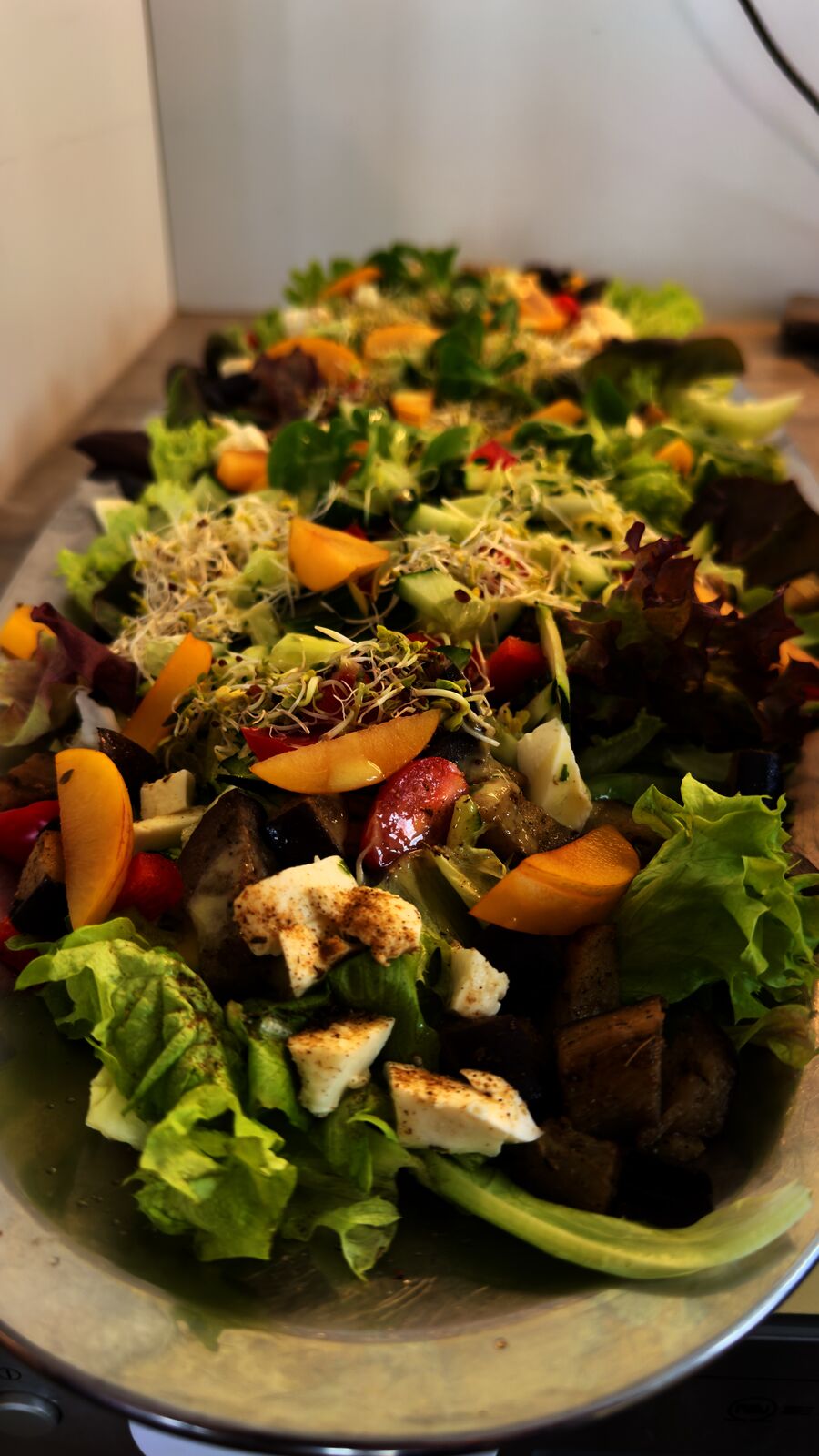 Bunter Salat mit Blattsalat, Sprossen, Obst und Fetakäse in einer länglichen Schale.