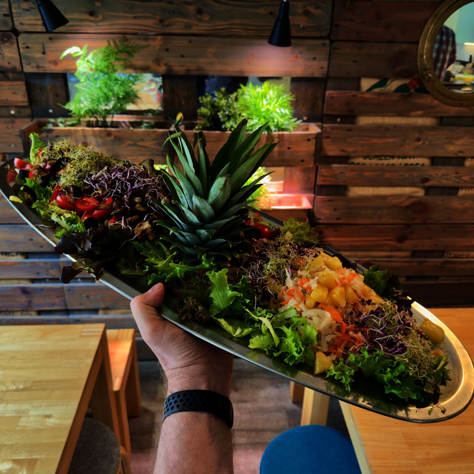 Buntes Salatbuffet mit Ananas in der Mitte und Sprossen auf rustikalem Holztisch.