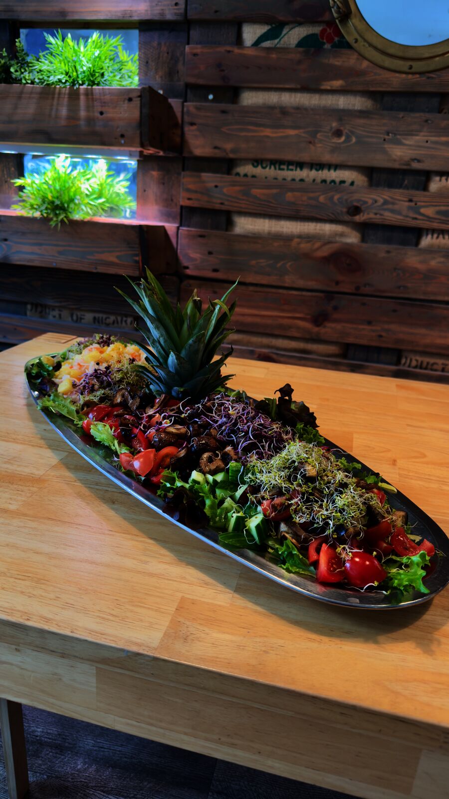 Großer bunter Salat mit Ananas und verschiedenen Gemüsesorten auf einer Holztheke.