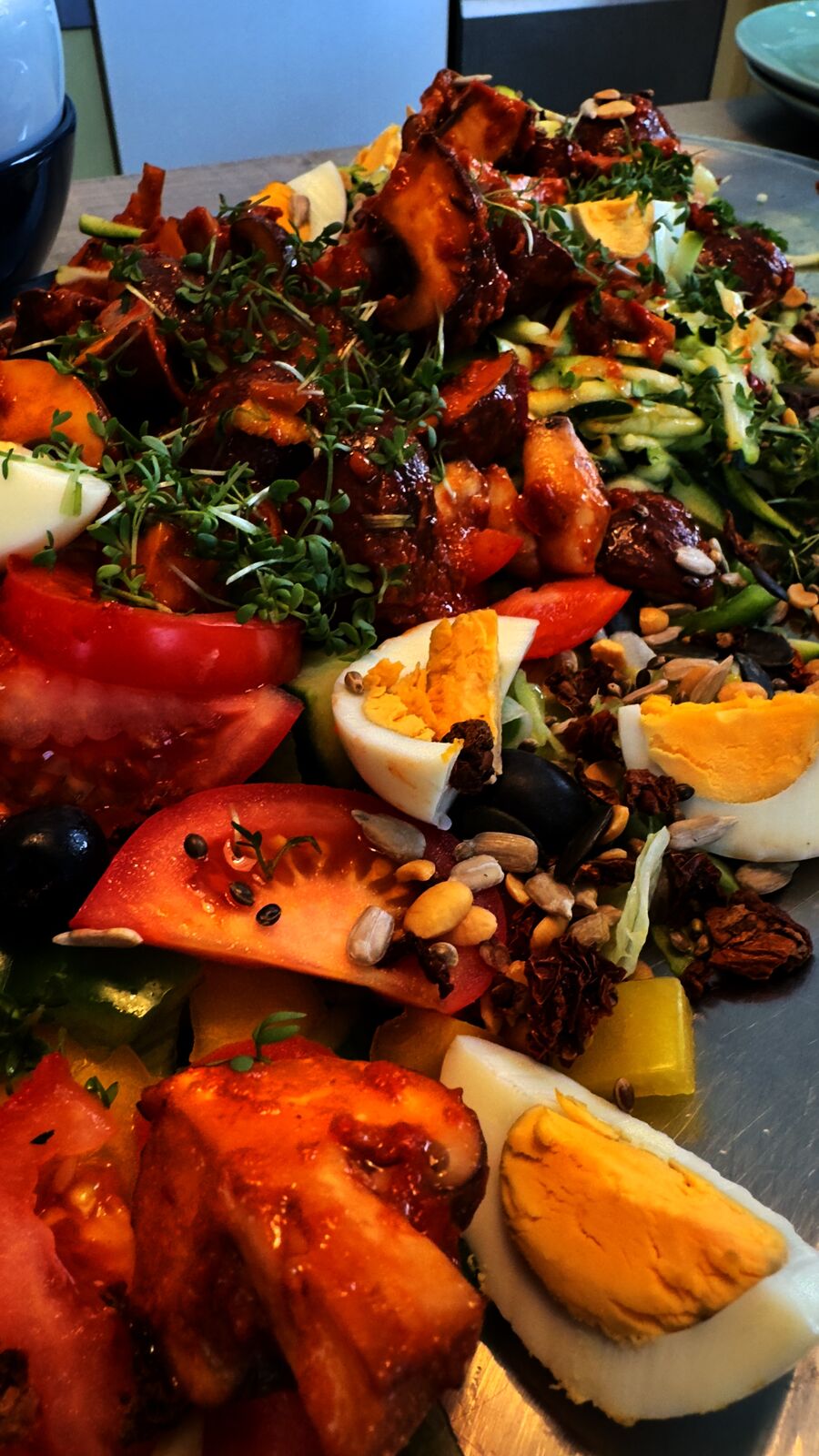Bunter Salat mit Tomaten, Gurkenstreifen, Ei, Kernen und mariniertem Hähnchen.