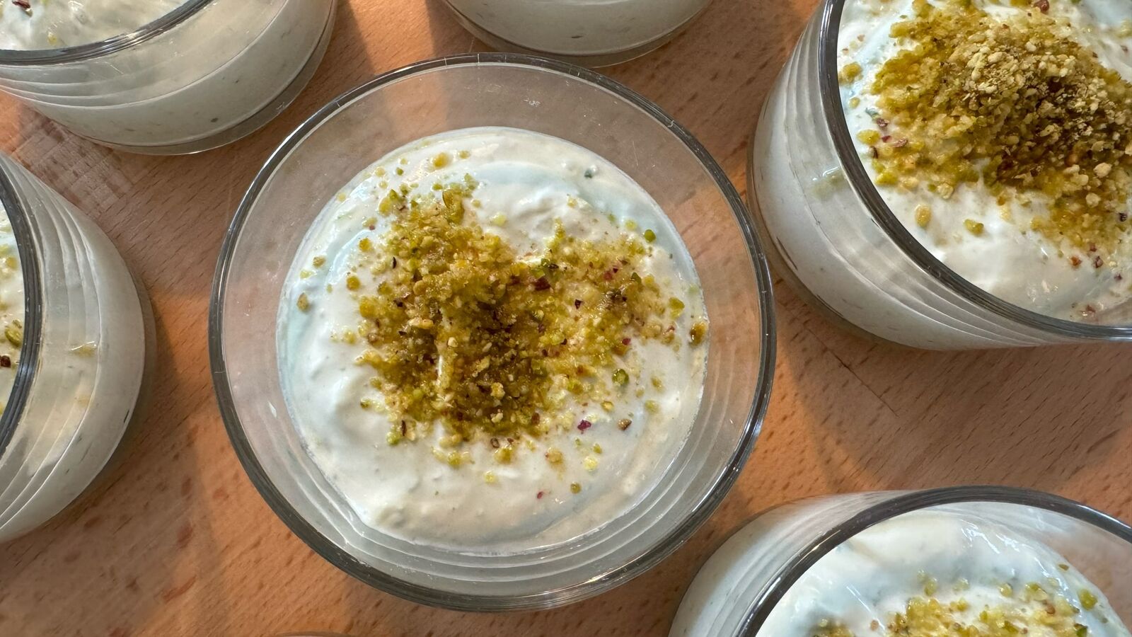 Dessertschalen mit pistachio-weißem Mousse auf Holztisch