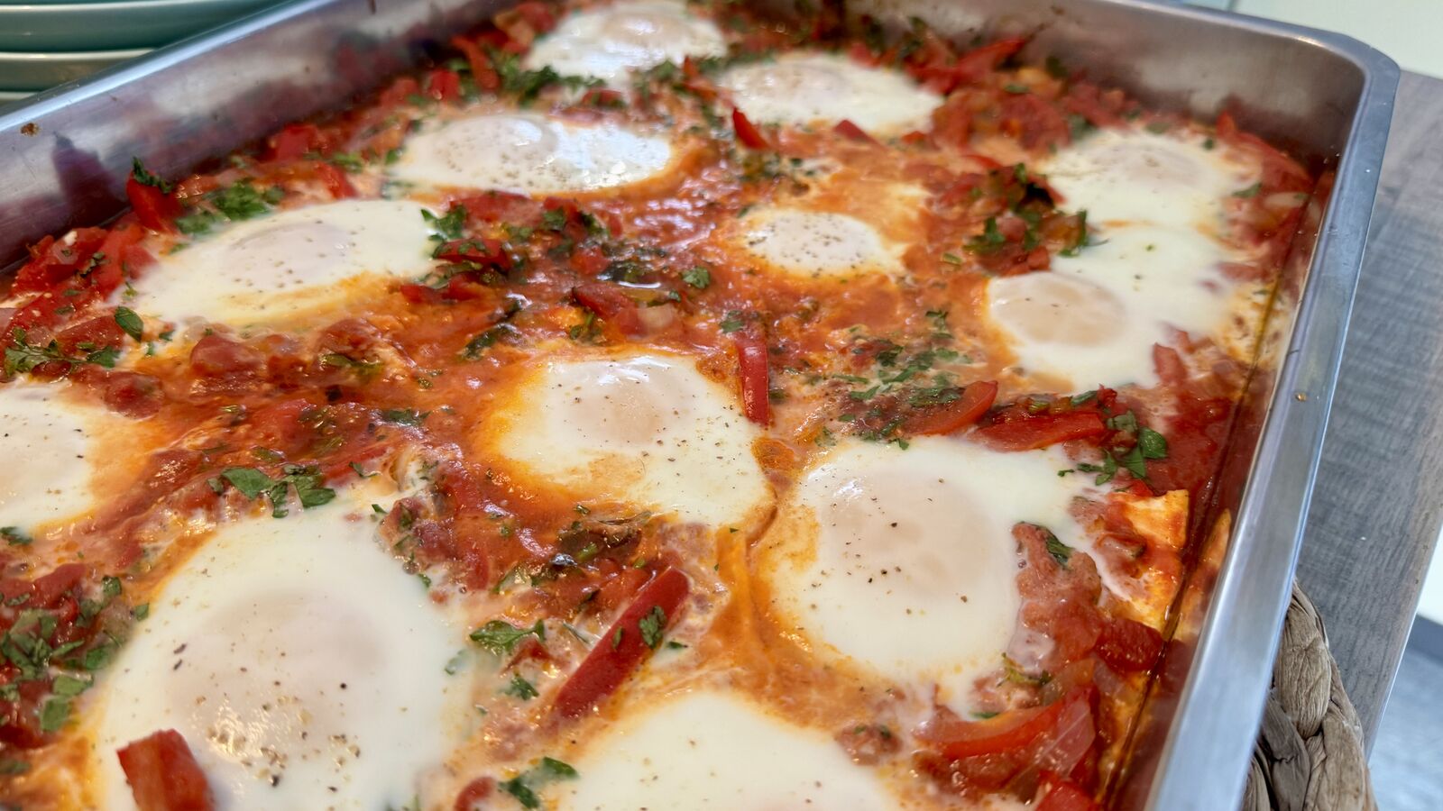 Ein Blech Shakshuka mit Tomatensauce, Paprika, Kräutern und pochierten Eiern.