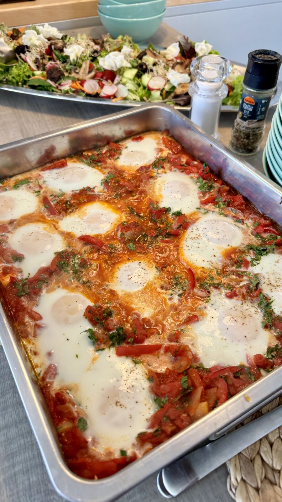 Eier in Tomatensauce mit Salat im Hintergrund auf einem Buffet angerichtet