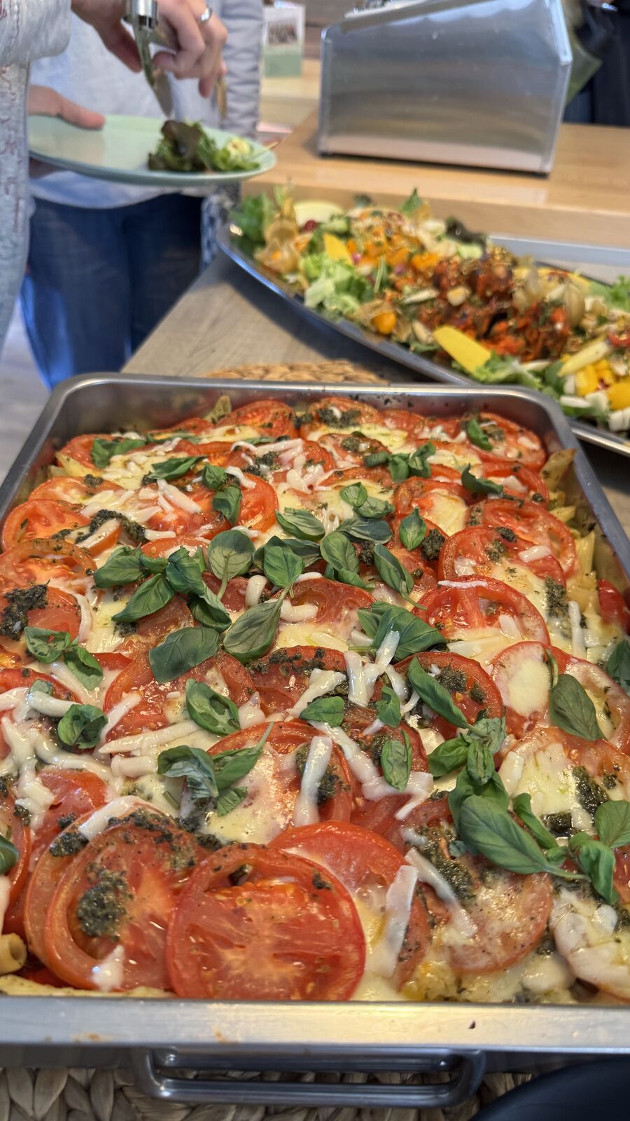 Auflauf mit Tomaten, Mozzarella und Basilikum in einem Buffet-Setup.