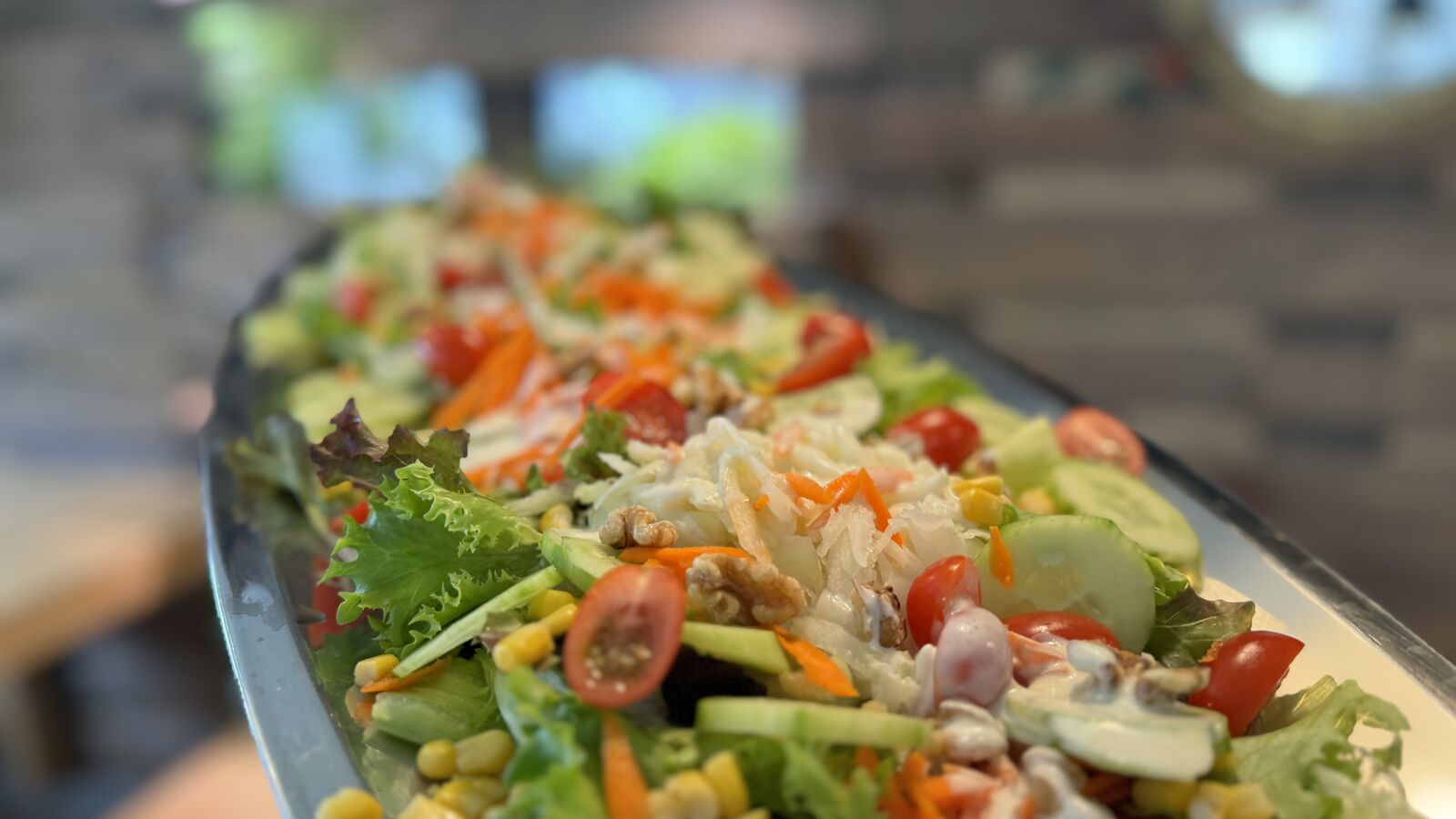 Buntes Salatbuffet mit Tomaten, Gurken, Mais, Karotten und Nüssen.